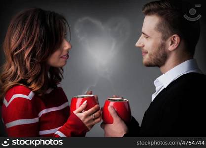 Young couple holding coffee mags with heart shaped steam, Valentine's day concept
