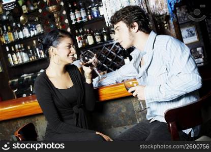 Young couple holding glasses of wine and looking at each other