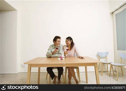 Young couple holding glasses of wine and looking at each other