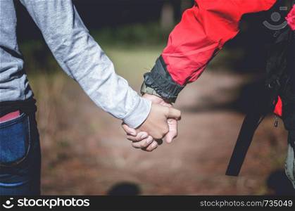 Young couple holding hands in forest, traveling concept