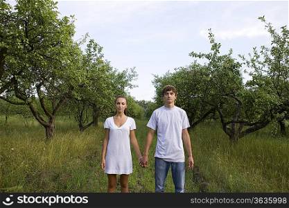 Young couple holding hands in orchard