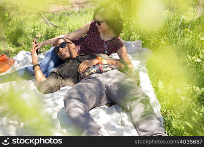 Young couple holding hands on picnic blanket in park