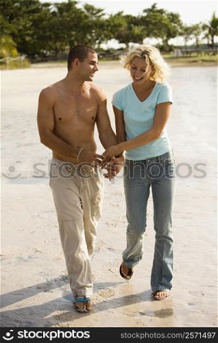 Young couple holding hands walking on the beach