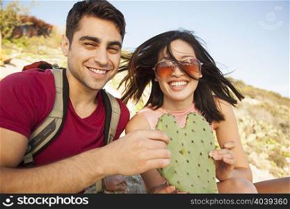 Young couple holding heart shaped cactus leaf
