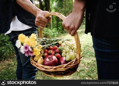 young couple holding picnic basket in outdoor park.