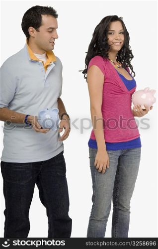 Young couple holding piggy banks