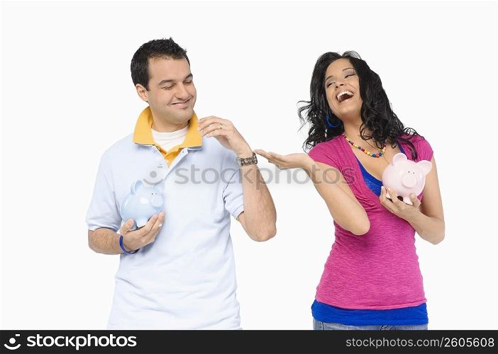 Young couple holding piggy banks and smiling