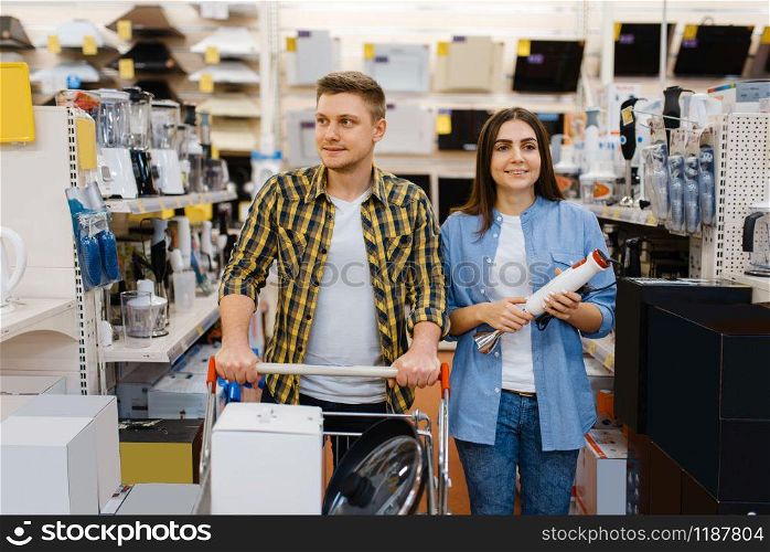 Young couple holds electric blender in electronics store. Man and woman buying home electrical appliances in market. Couple holds electric blender in electronics store