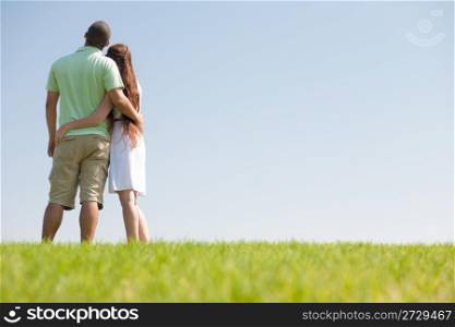 young couple hug and look at the sky
