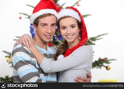 Young couple hugging by Christmas tree