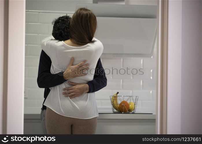young couple hugging in the kitchen of their house. concept of psychological help
