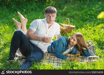 Young couple hugging on the grass and looking at each other during a picnic in a city park