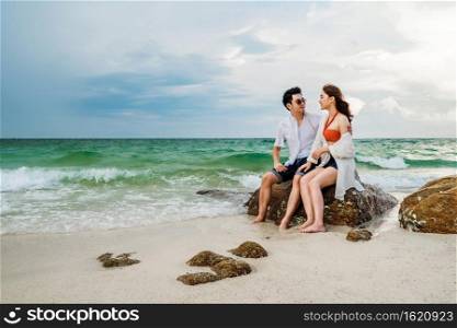 young couple hugging on the rock of sea beach at Koh MunNork Island, Rayong, Thailand