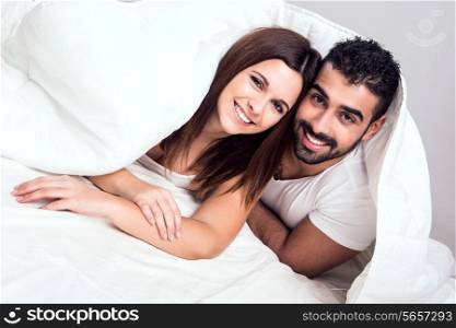 Young couple hugging while lying in bed in the morning