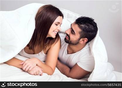 Young couple hugging while lying in bed in the morning