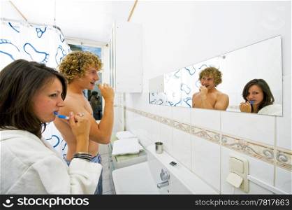 Young couple in a bathroom brushing their teeth together