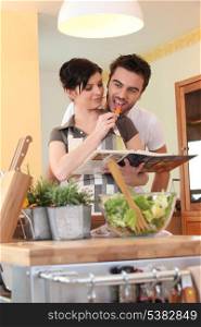 Young couple in a kitchen with a cookbook