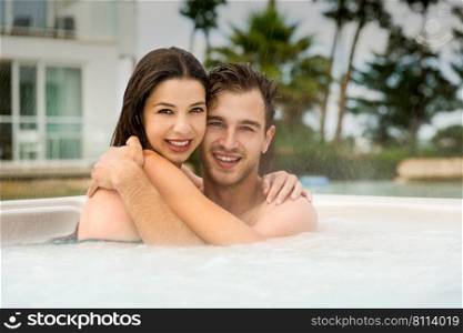 Young couple in a luxury hotel embraced inside a jacuzzi and enjoying the holidays