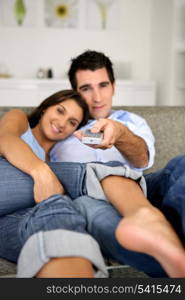 Young couple in a sofa watching TV