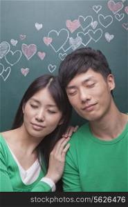 Young couple in front of blackboard with hearts