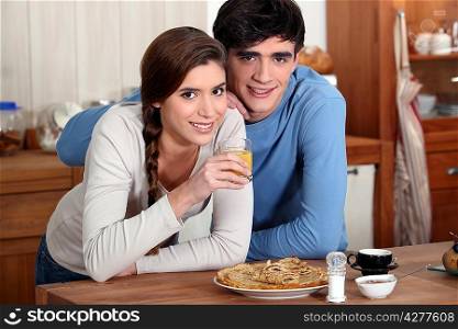 Young couple in kitchen eating pancakes