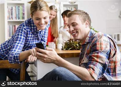 Young couple in kitchen with cell phone