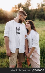 young couple in love a guy with a beard and a girl with dark hair in light clothes in the green forest