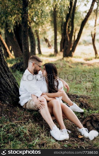 young couple in love a guy with a beard and a girl with dark hair in light clothes in the green forest