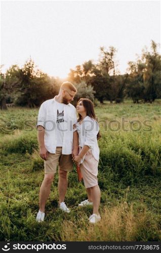 young couple in love a guy with a beard and a girl with dark hair in light clothes in the green forest