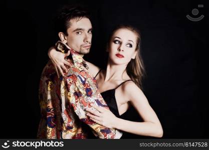 Young couple in love dancing on black background