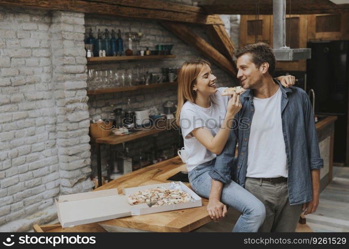 Young couple in love eating pizza for sneck in the rustic home