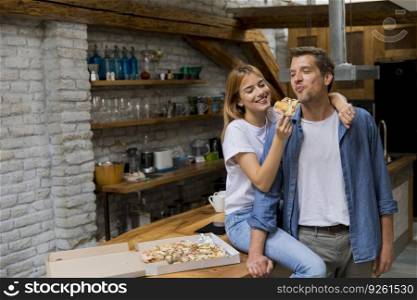 Young couple in love eating pizza for sneck in the rustic home