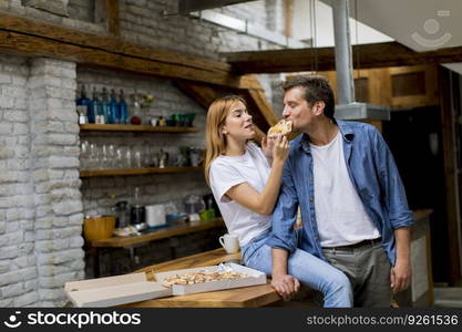 Young couple in love eating pizza for sneck in the rustic home