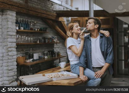 Young couple in love eating pizza for sneck in the rustic home