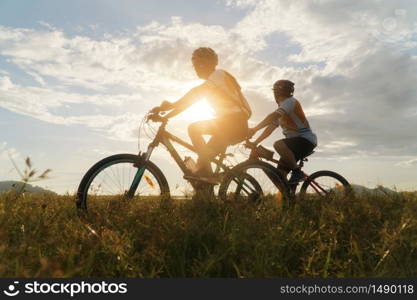 Young Couple in love fun and happy riding mountain bike after covid-19 coronavirus outbreak. End of the coronavirus outbreak. Silhouette cycling man and woman riding mountain bike at sunset time.