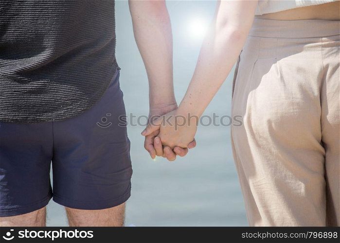 Young couple in love holding hands looking in the sunset closeup. Young couple in love holding hands looking in the sunset