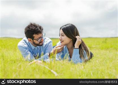 Young couple in love lying on the grass touching each other’s faces, two people in love lying on the grass looking at each other, A couple lying on the grass looking at each other