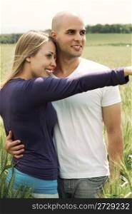 Young couple in meadow with the hands in the air, hugging in the park