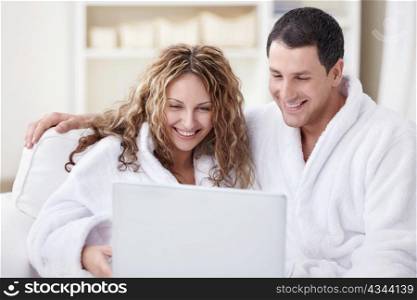 Young couple in overalls looking at laptop