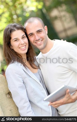 Young couple in public park with electronic tablet