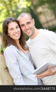 Young couple in public park with electronic tablet