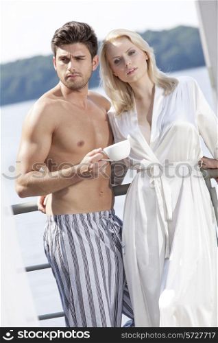 Young couple in sleepwear having coffee on hotel balcony