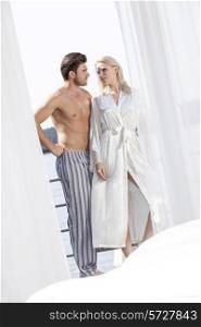 Young couple in sleepwear looking at each other on hotel balcony