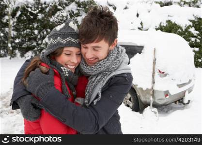 Young couple in snow with car