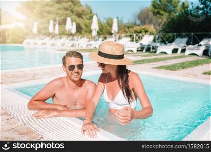 Young couple in swimming pool enjoying summer vacation. Happy family of two in outdoor pool. Cheerful couple resting in a swimming pool