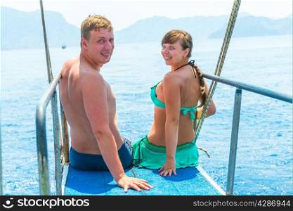 young couple in swimsuits on a yacht at sea
