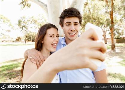 Young couple in the park. Young couple in the park making their selfi with mobile phone