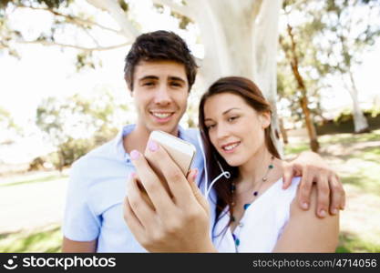 Young couple in the park. Young couple in the park making their selfi with mobile phone