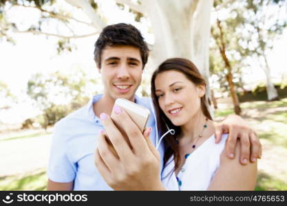 Young couple in the park. Young couple in the park making their selfi with mobile phone