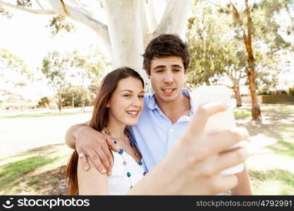 Young couple in the park. Young couple in the park making their selfi with mobile phone